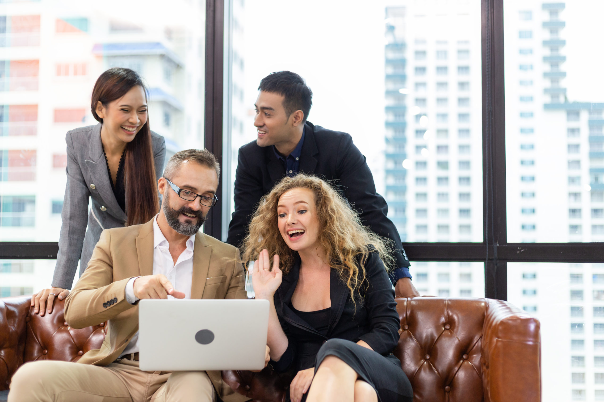 Corporate employees gathered around a computer laughing